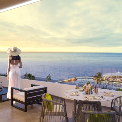 Bir kadın okyanusa bakan balkonda oturuyor.